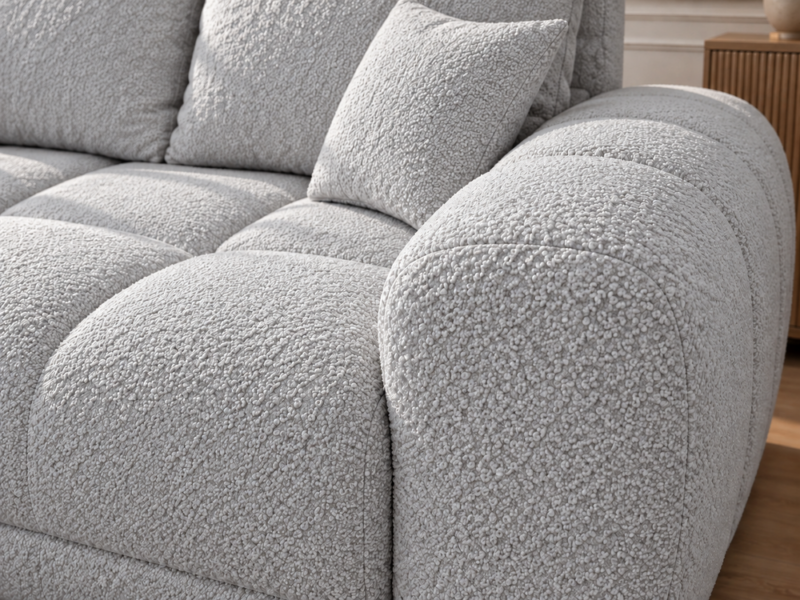 Jasnoszara sofa boucle w zbliżeniu Narożnik z funkcją spania i pojemnikiem Aurio lewy szary boucle