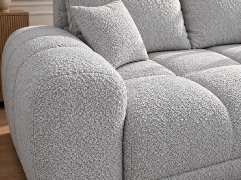 Jasnoszara sofa boucle w zbliżeniu_PRAWY Narożnik z funkcją spania i pojemnikiem Aurio prawy szary boucle