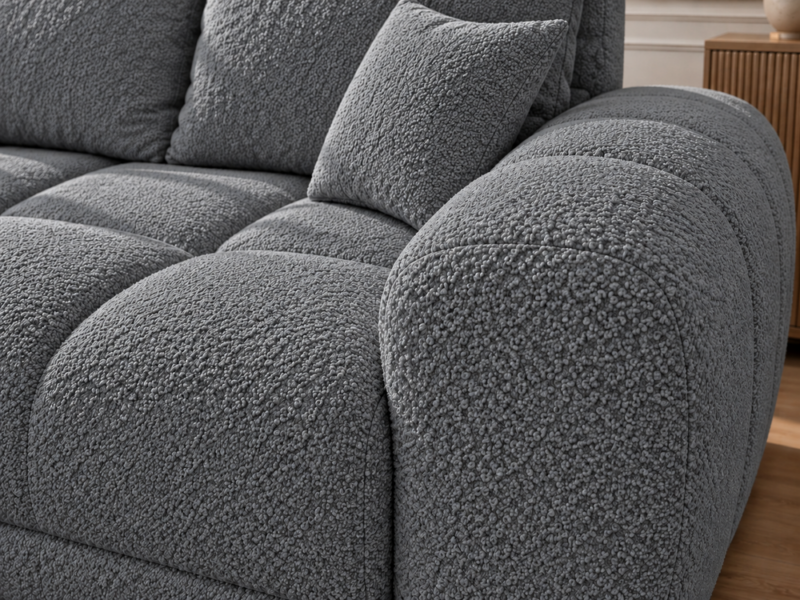 Szara sofa boucle w zbliżeniu Narożnik z funkcją spania i pojemnikiem Aurio lewy ciemnoszary boucle
